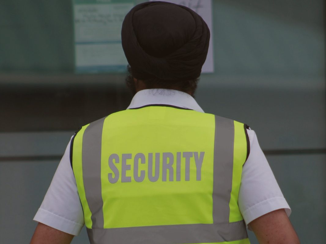 Secure 24 Seven guard seen from behind wearing a high-visibility vest marked SECURITY